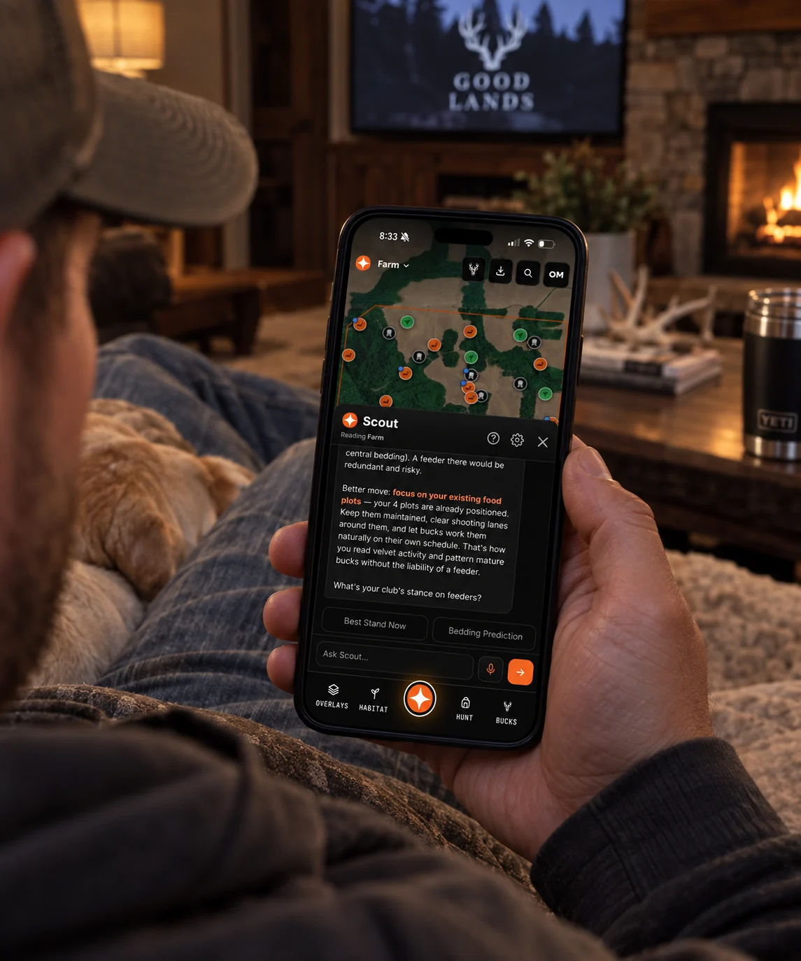 A hunter at home by the fire reading a Scout answer about his food plots on a mapped property